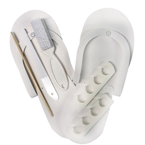 A pedicure kit including white pedi slippers, toe separators, a manicure brush, a plastic file, and a birchwood stick, all arranged in a heart-shaped holder.