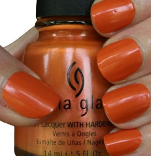 China Glaze orange nail polish bottle with orange nail polish on a hand