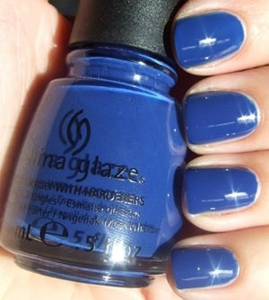 China Glaze blue nail polish bottle held by a hand with blue nails