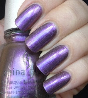 Purple nail polish with a hand holding the bottle, showing metallic finish.