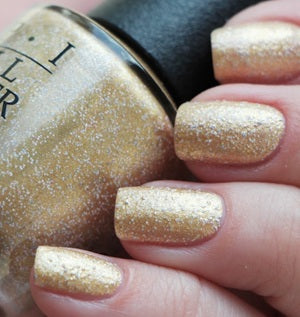 Gold glitter nail polish bottle and nails with gold glitter finish