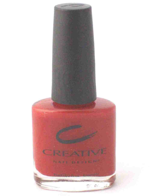 A bottle of vivid red creme nail color, with the brand Creative Nail Design visible on the label.