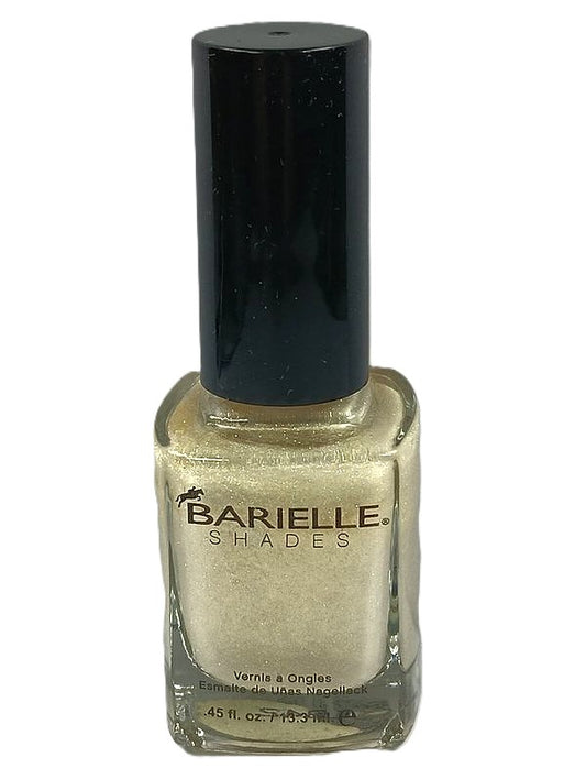 A bottle of Barielle nail polish in color Uninhibited 5028, displaying a very light gold nail polish with golden shimmer.