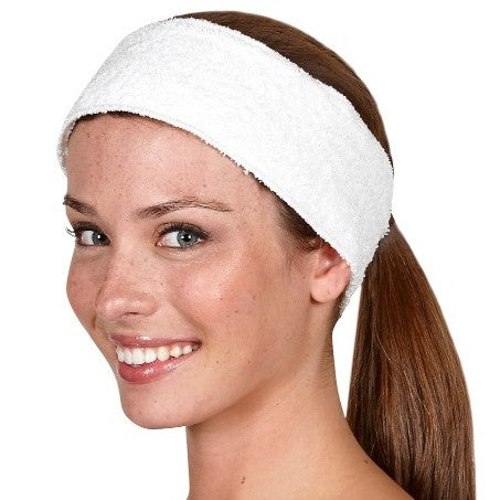 A woman wearing a white terrycloth spa headband with an adjustable Velcro closure.