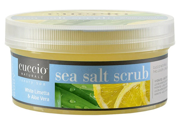 Cuccio Naturale sea salt scrub container with lemon slices and green leaves on a white background