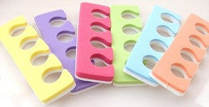 An assortment of disposable foam toe separators in various colors including pink, purple, green, yellow, orange, and blue.