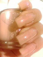 A bottle of Essie nail polish color beige nude with pink shimmer, painted on nails.
