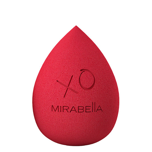A red-colored Mirabella precision makeup sponge with the brand's logo and a small 'X' symbol on the surface.