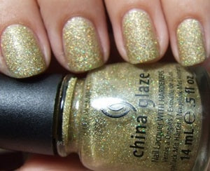 Gold glitter nail polish bottle with a hand displaying nails painted with the same color.