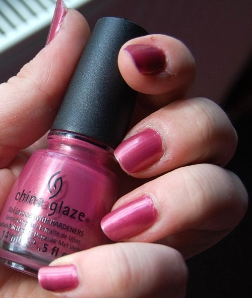 Hand holding a bottle of China Glaze nail polish with pink nails.