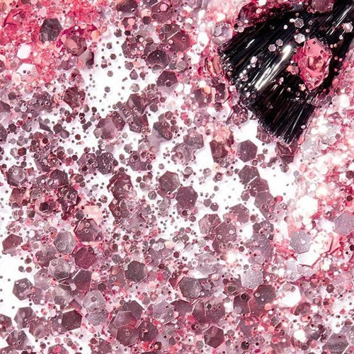 Pink glitter with a black bottle cap on a pink and white speckled background