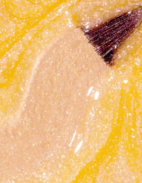 Close-up of an orange shimmer nail polish swatch with brush.