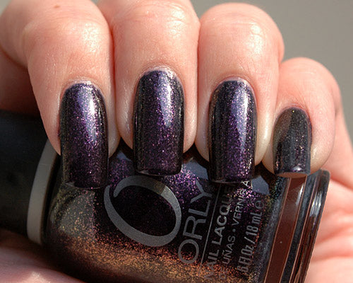 Nail polish bottle with purple glittery nail polish on nails